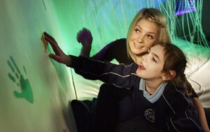 Woman with girl in multi-sensory room.