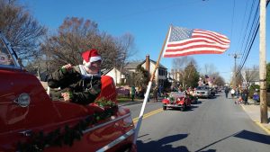 Red motorcycle riding in Christmas parade while towing American flag.