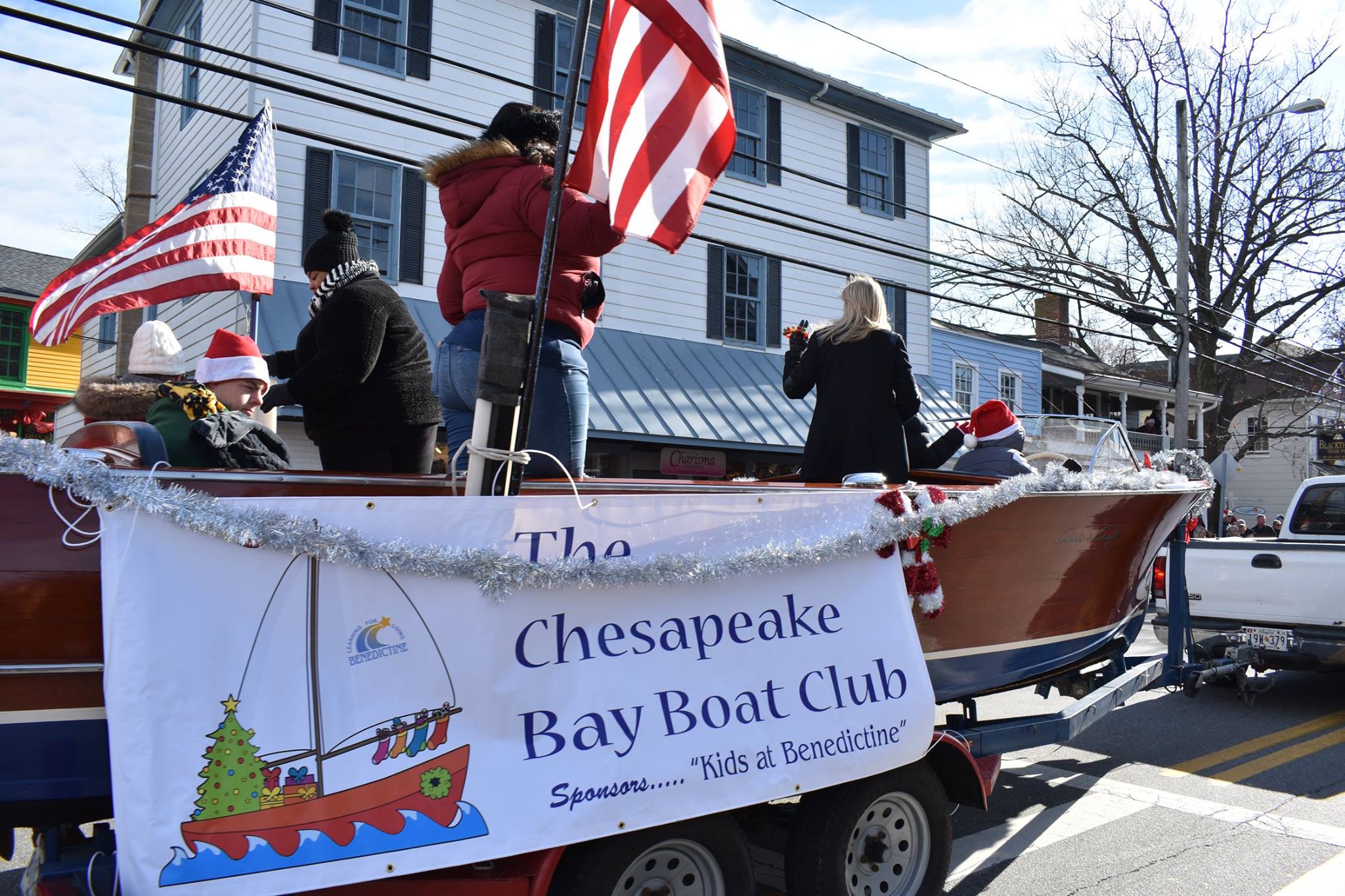 Boat on trailer in parade with Chesapeake Bay Boat Club banner.