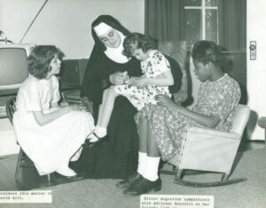 Sister Augustine Kern sitting with three young girls.