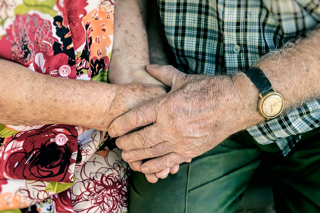 Closeup of two elderly people holding hands.