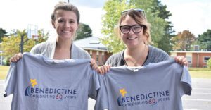 Young women smiling, holding Benedictine T Shirts.